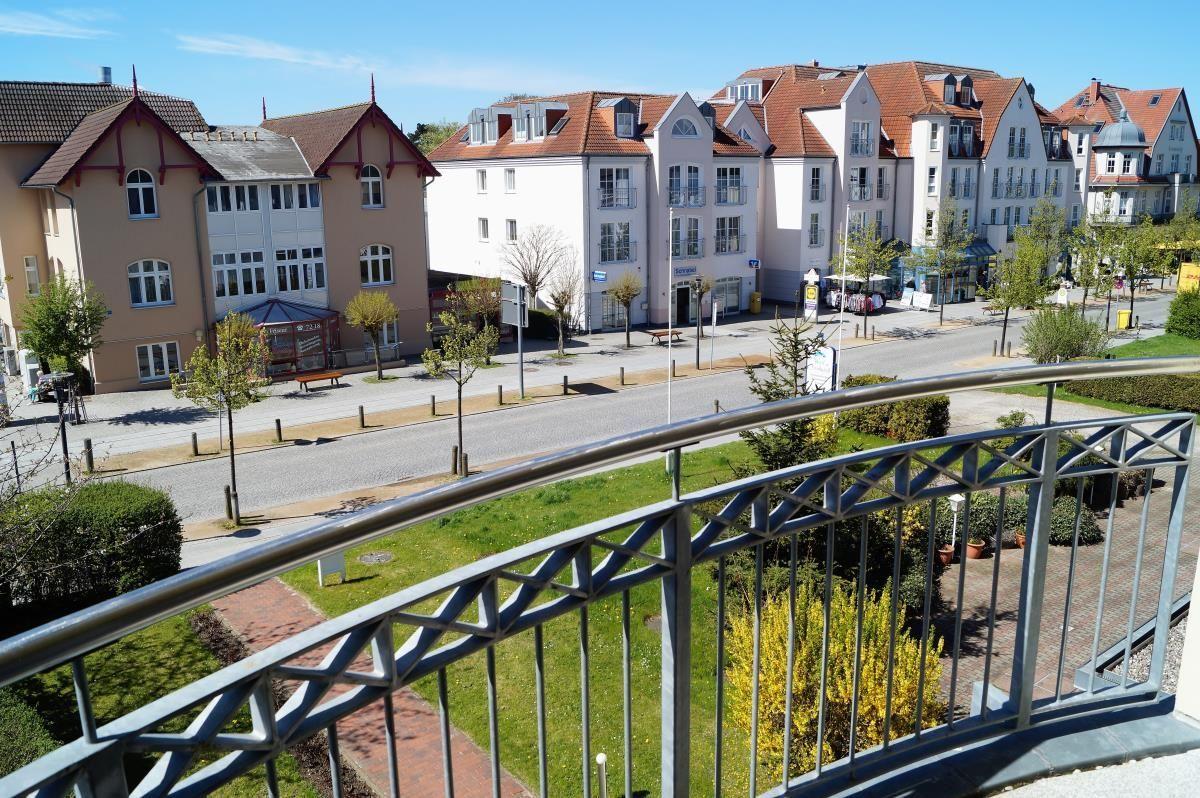 Blick von Balkon auf Straße mit Häusern und Grünflächen