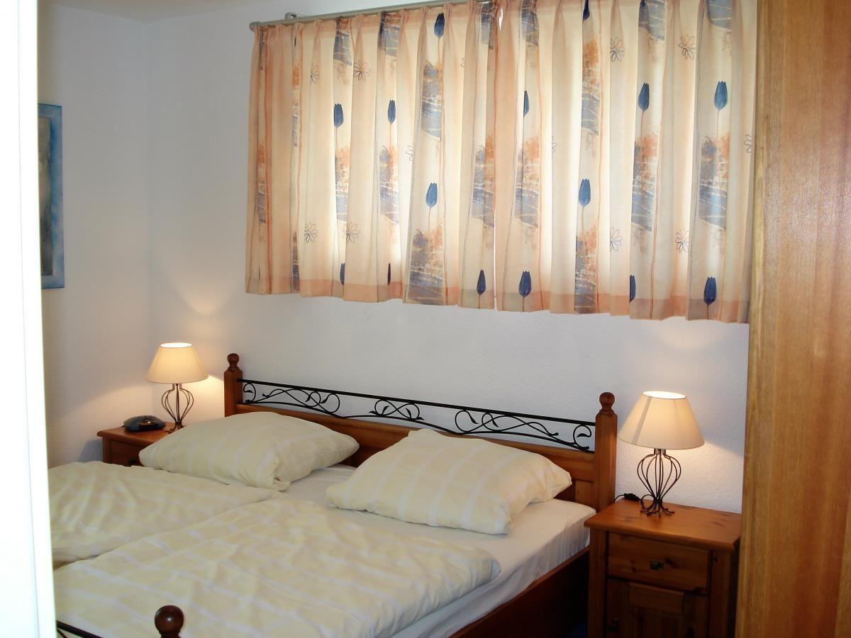 Ein Schlafzimmer mit Doppelbett, zwei Nachttischen und Vorhängen mit Blumenmuster.