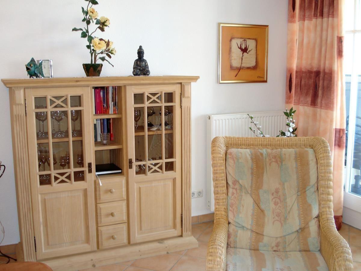 Holzschrank mit Glaseinsätzen und Stuhl mit Muster