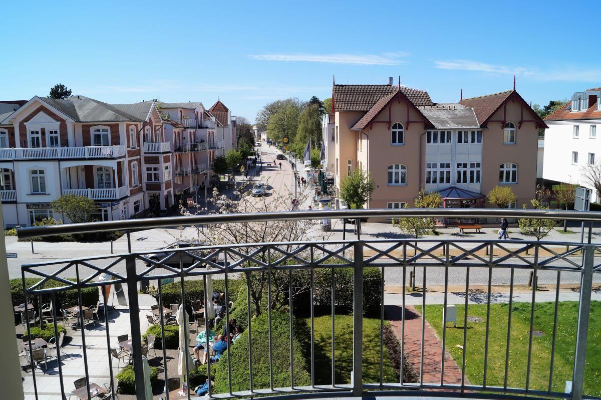 Balkon mit Blick auf eine Straße mit Häusern und Grünflächen.