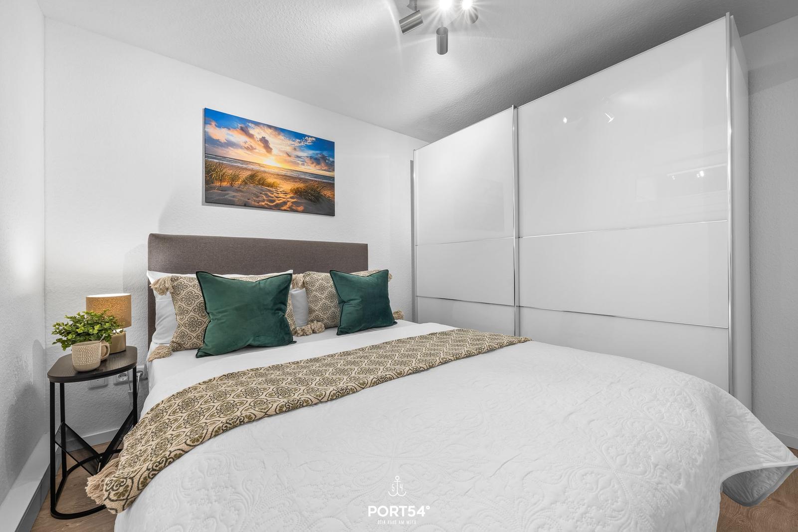 Schlafzimmer mit Bett, Kleiderschrank und Wandbild