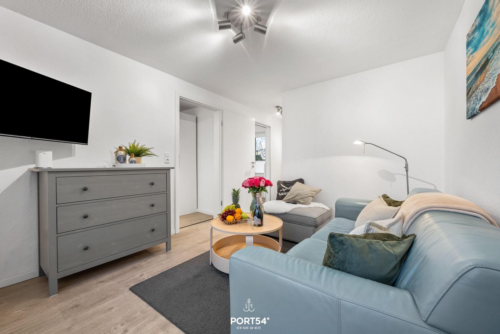 Wohnzimmer mit Sofa, Couchtisch und Fernseher an der Wand.