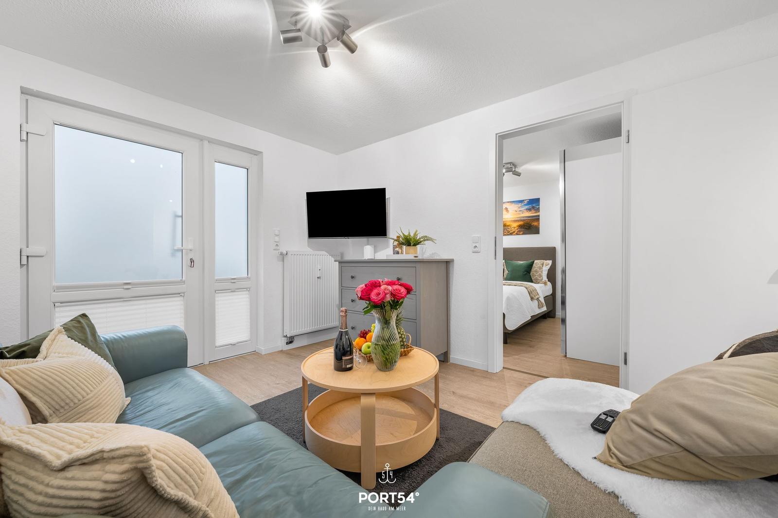 Wohnbereich mit Sofa, Couchtisch und Fernseher. Durchgang zur Schlafzimmer.