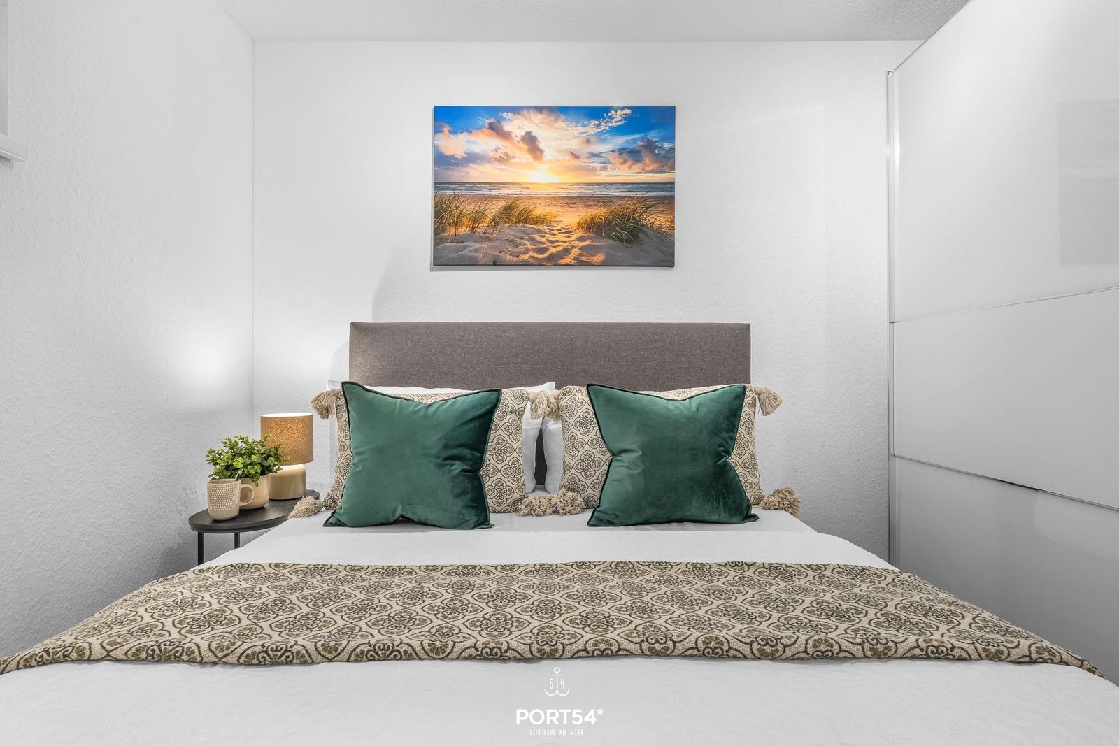 Schlafzimmer mit Bett, Kissen und Wandbild