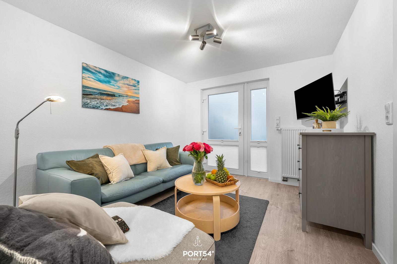 Wohnzimmer mit Sofa, Couchtisch und Fernseher an der Wand.