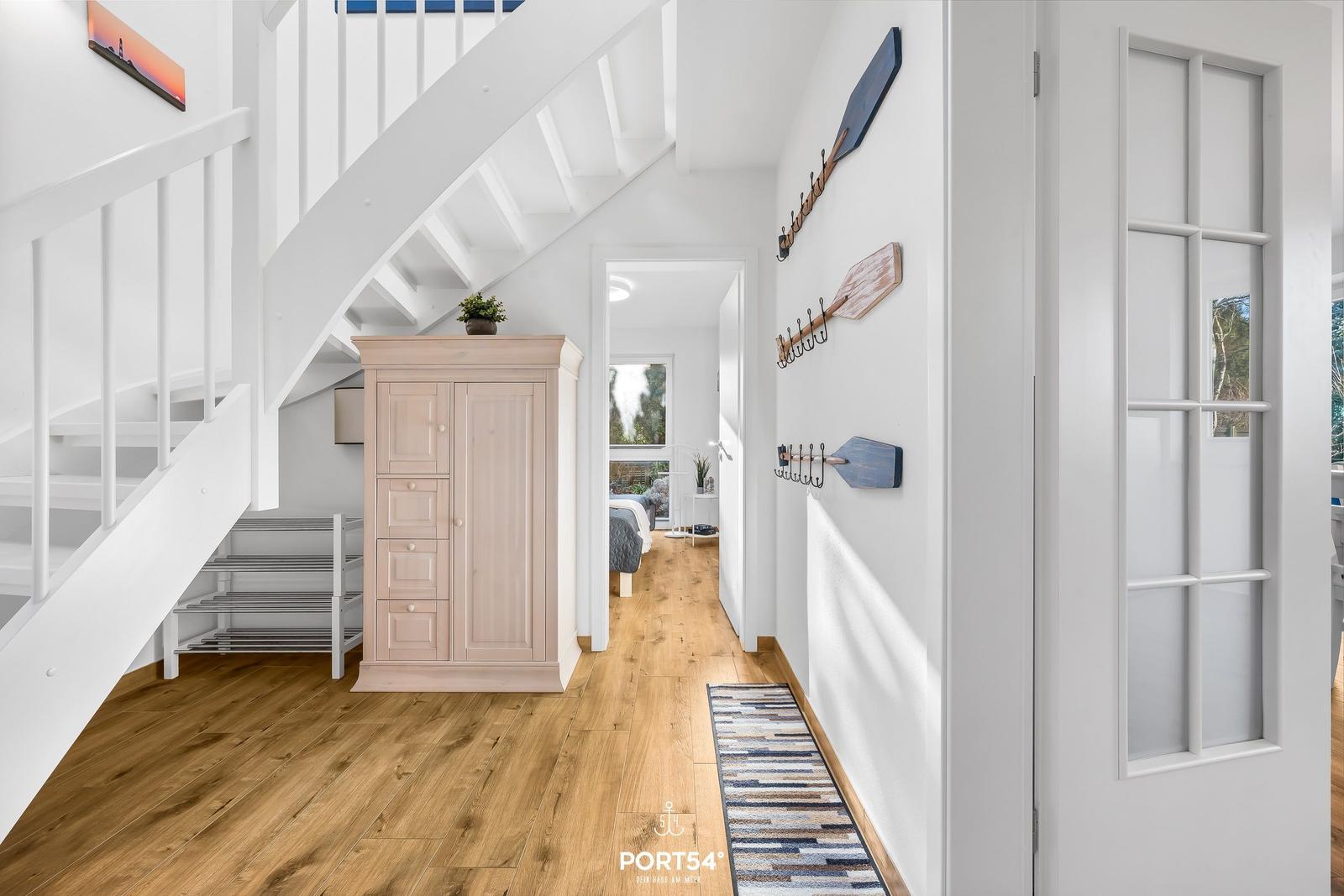 Flur mit Holzboden, Kleiderschrank und Treppe zur oberen Etage.