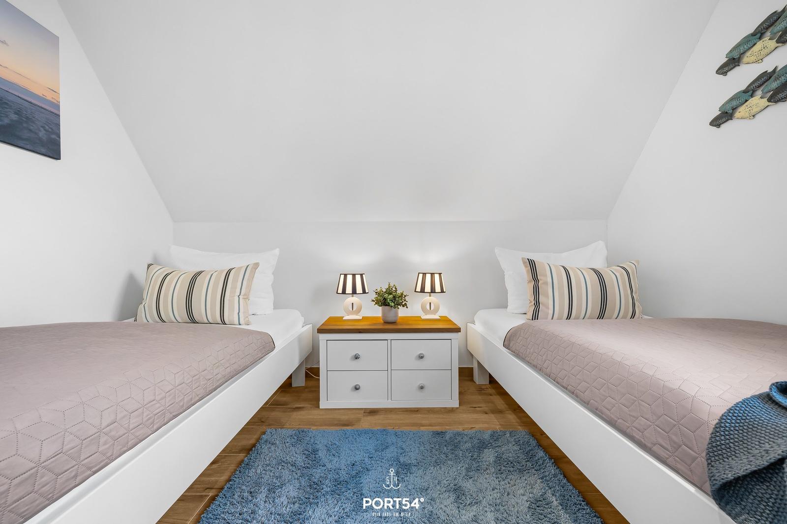 Zwei Betten mit Streifenkissen und Nachttisch mit Lampen.