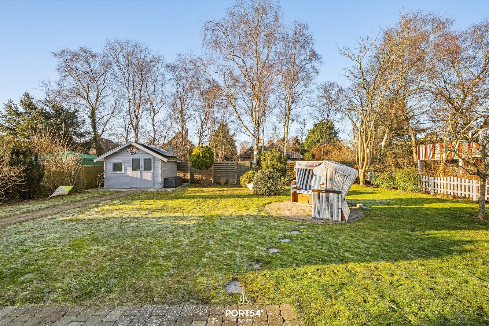 Hinterhof mit Gartenhaus und Strandkorb auf Rasenfläche.