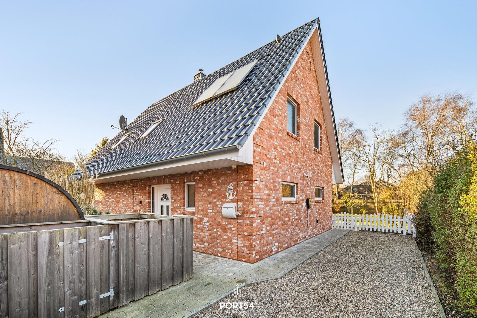 Rotes Backsteinhaus mit schwarzem Dach und Gartenbereich.