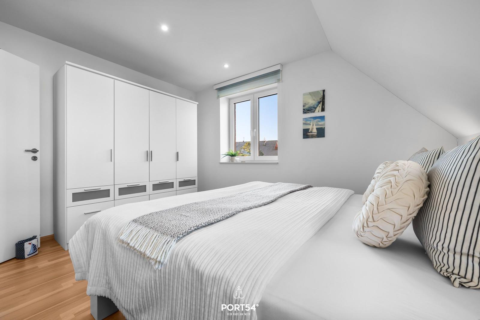 Schlafzimmer mit Bett, Kleiderschrank und Fenster mit Blick.