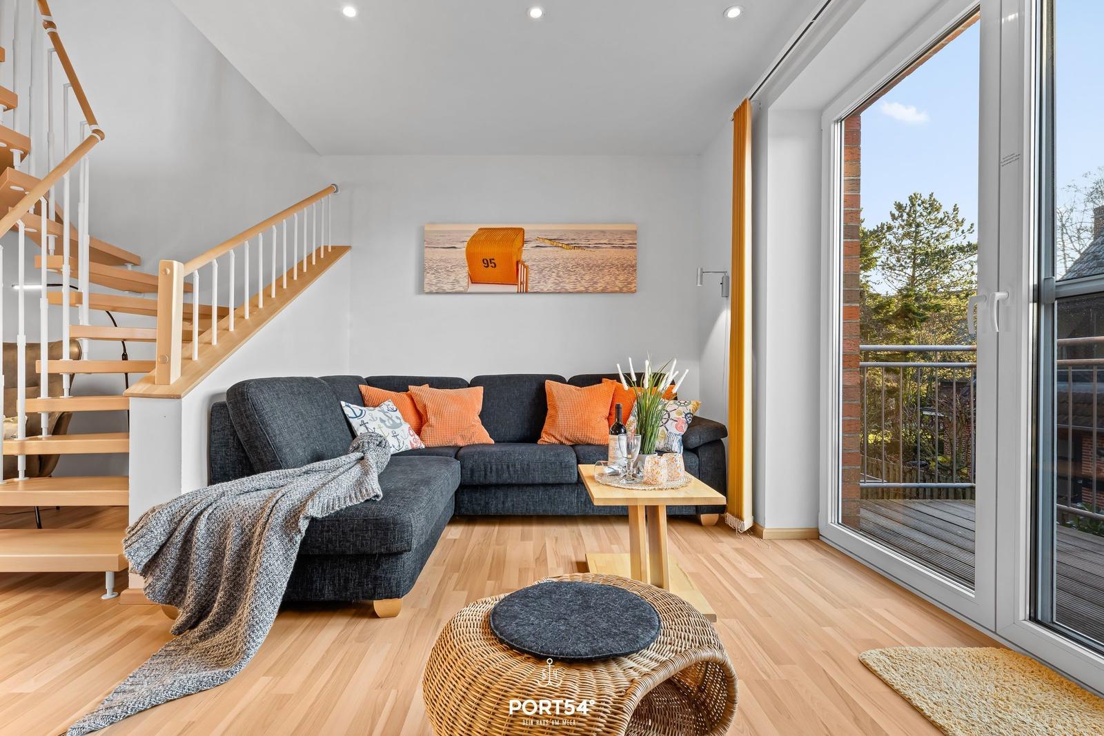 Wohnzimmer mit Sofa, Tisch und Blick auf Balkon.