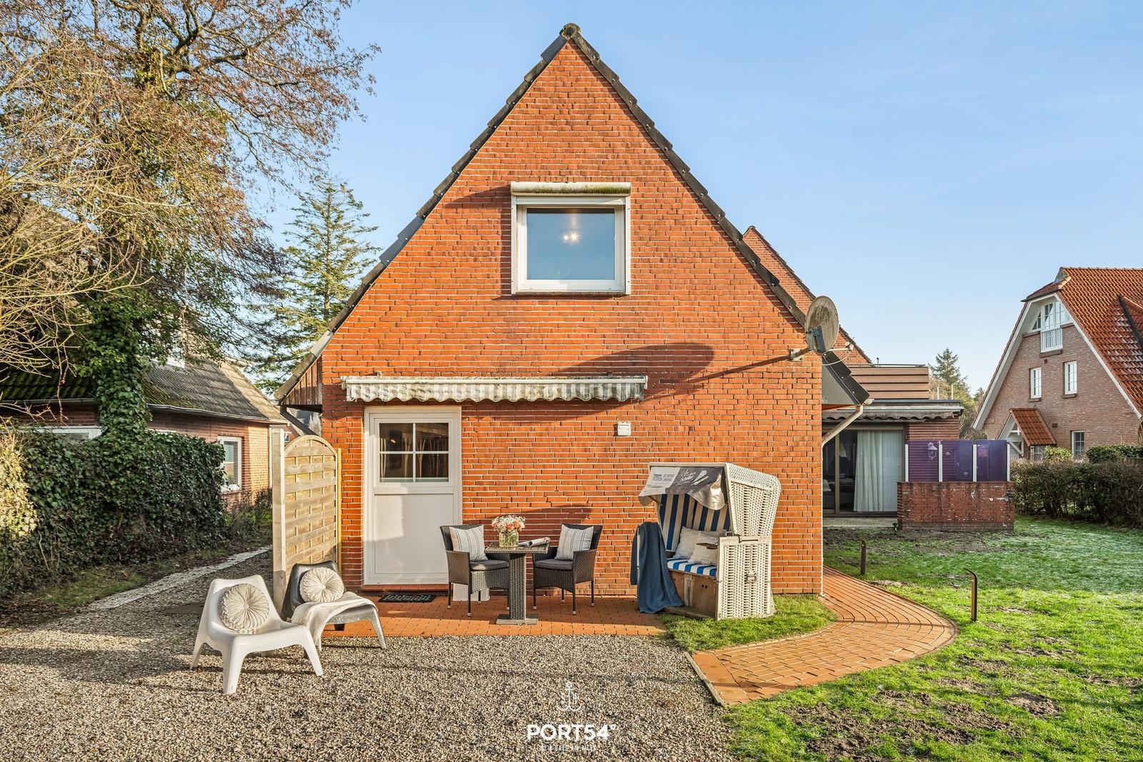 Rotes Backsteinhaus mit Terrasse, Strandkorb und Garten.