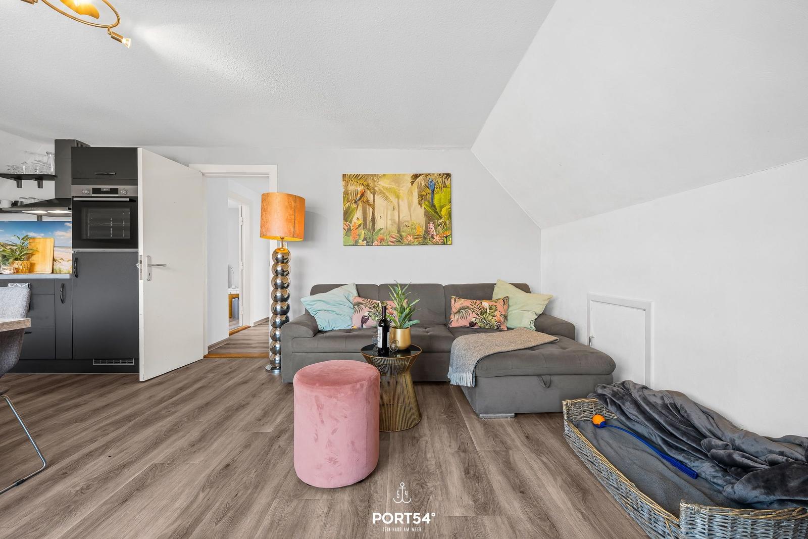 Wohn- und Küchenbereich mit Sofa, Kamin und Holzboden.