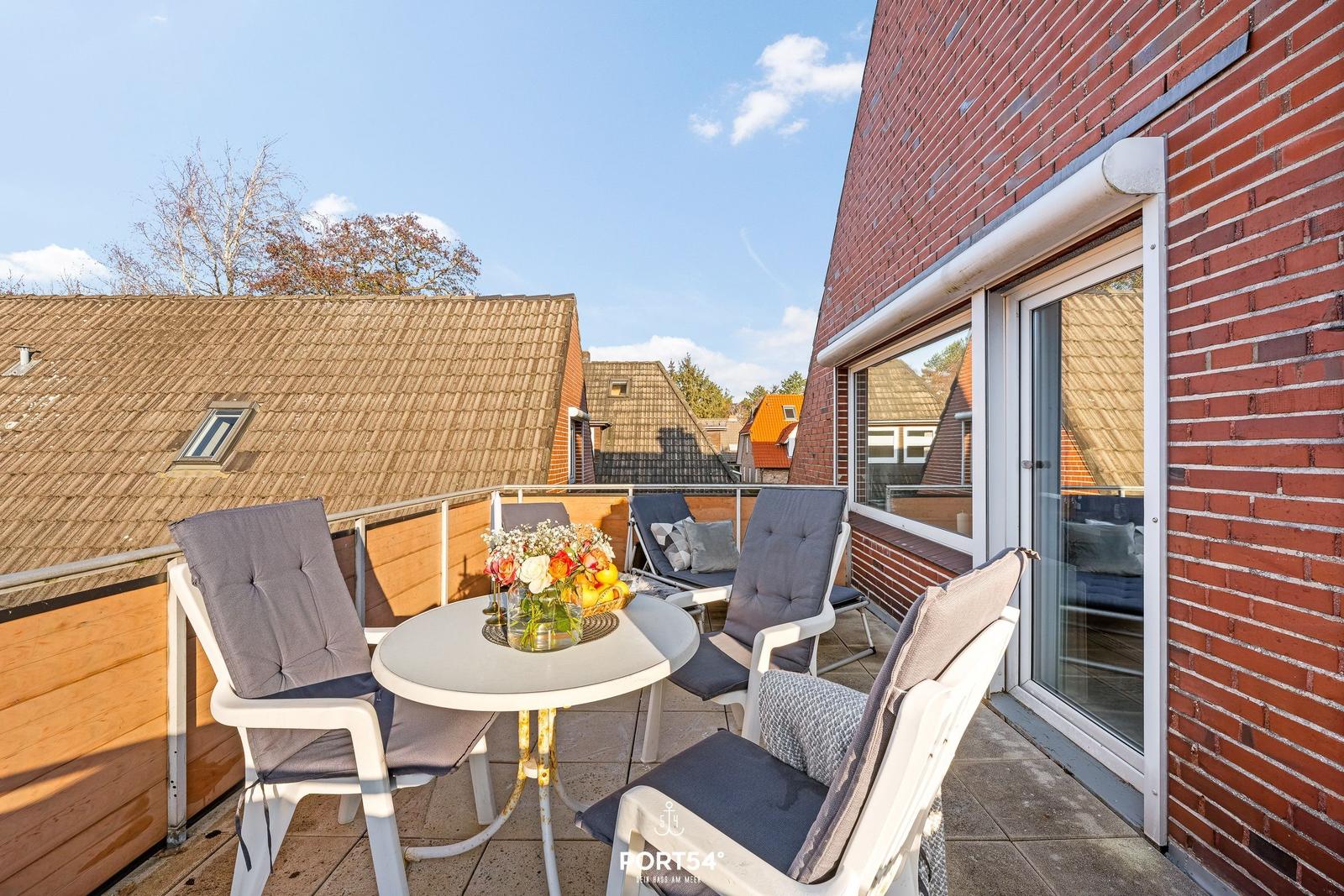 Terrasse mit Tisch, Stühlen und Blick auf Dächer.