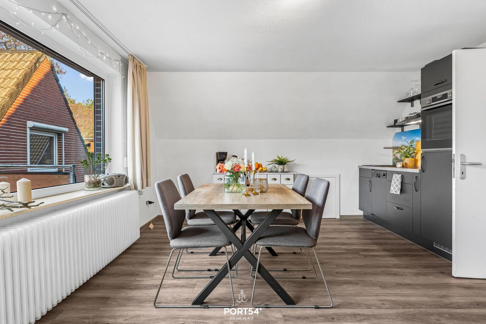 Essbereich mit Tisch und Stühlen, Küche mit Geräten und Fensterblick.