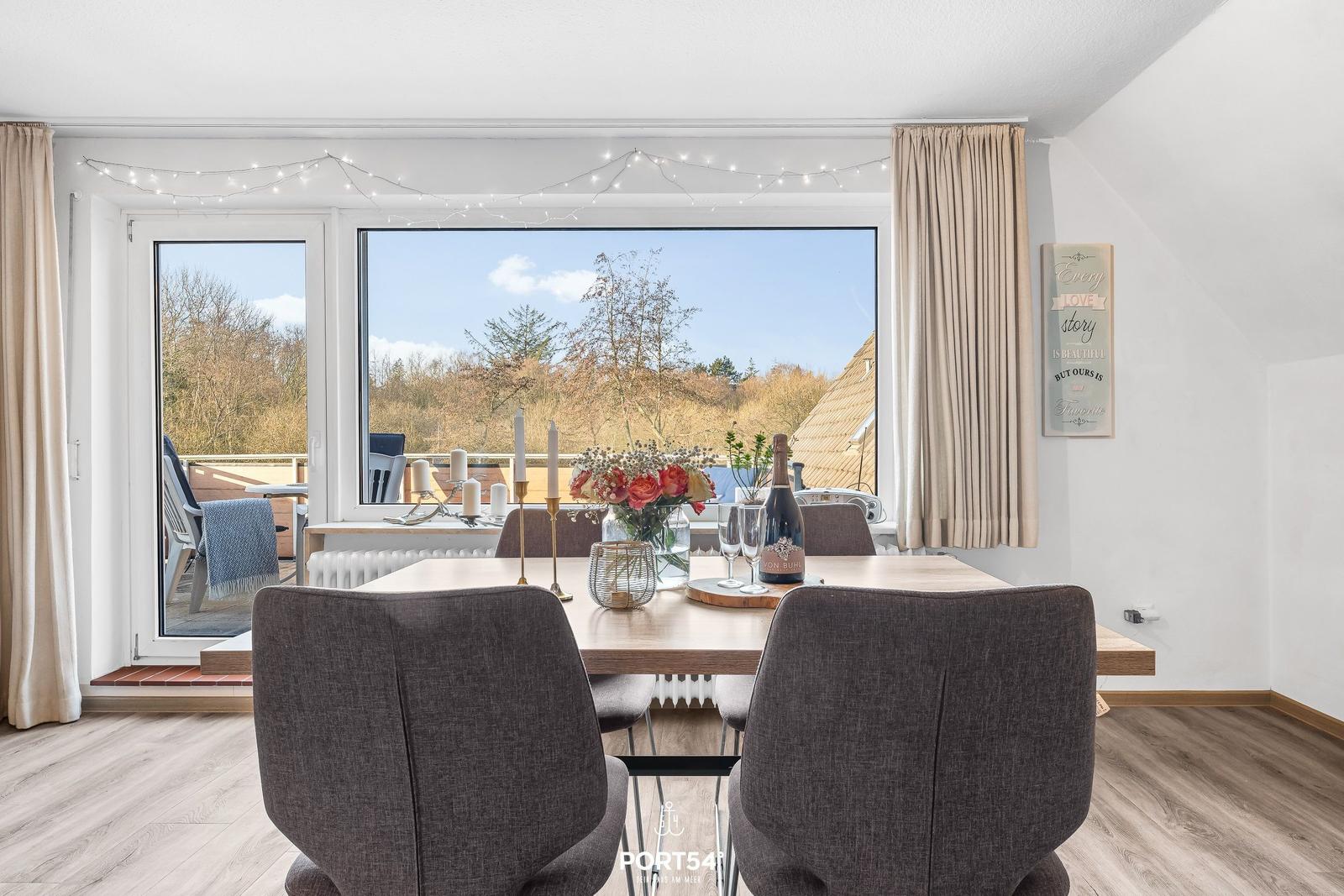 Esszimmer mit Tisch, Stühlen und Aussicht auf Balkon und Wald.