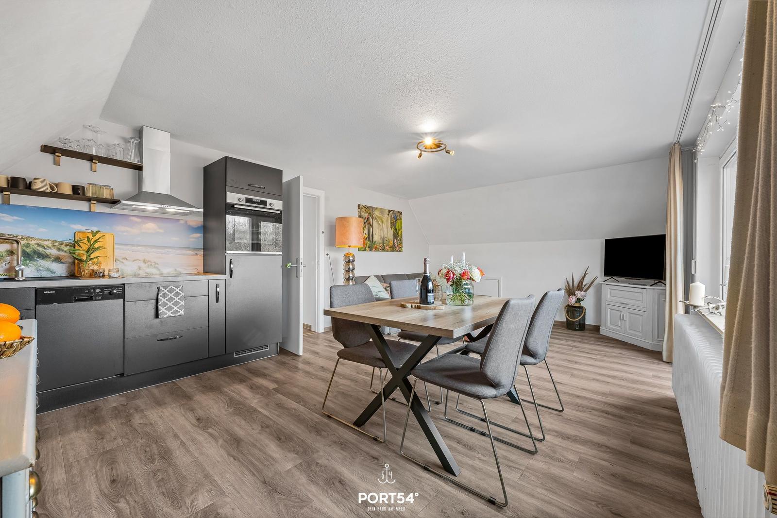 Küche mit Esstisch, Sofa und Fernseher in einem Raum mit Holzboden.