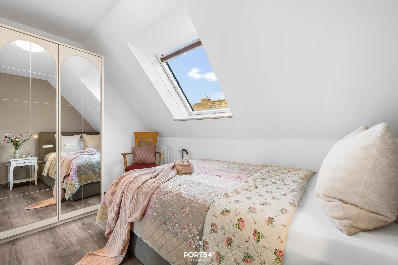 Schlafzimmer mit Dachschrägen, Dachfenster und Spiegelschrank.