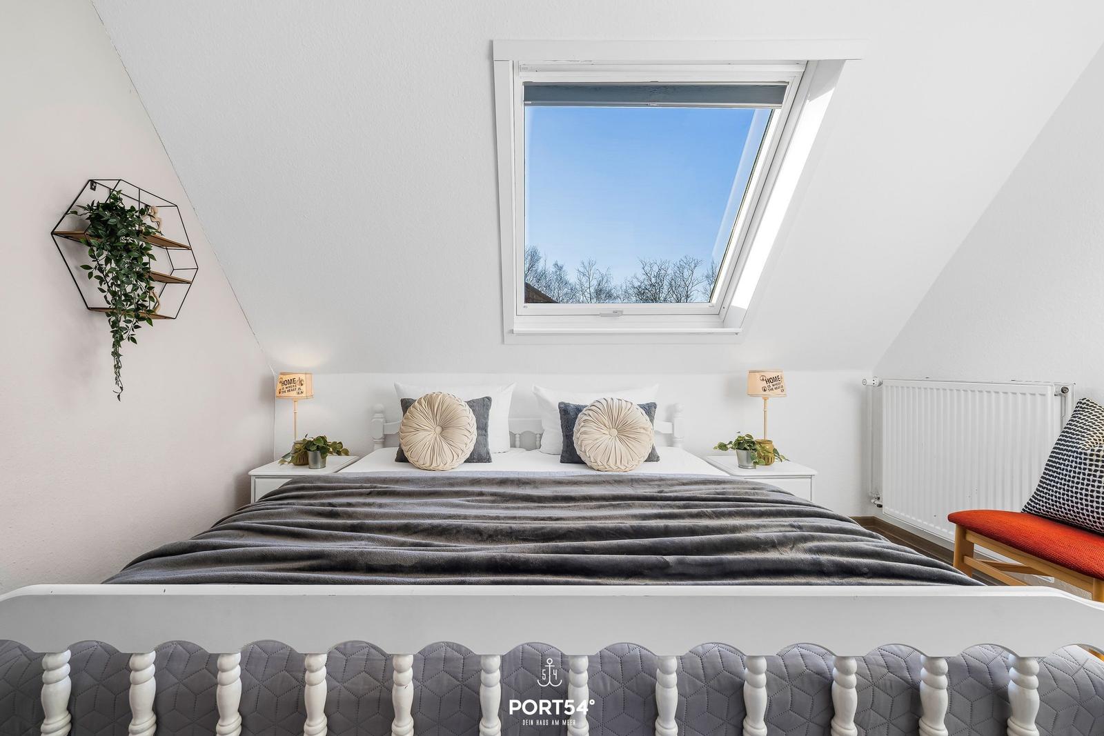 Dachgeschosszimmer mit Dachfenster, Bett und Sitzbank.