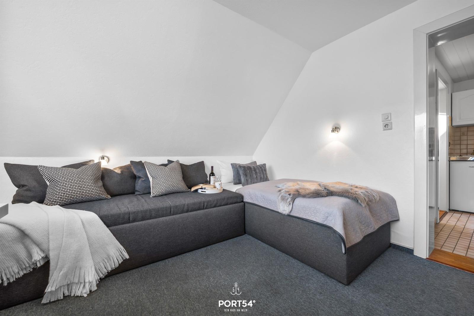 Schlafzimmer mit Schlafcouch und Einzelbett unter Dachschrägen.