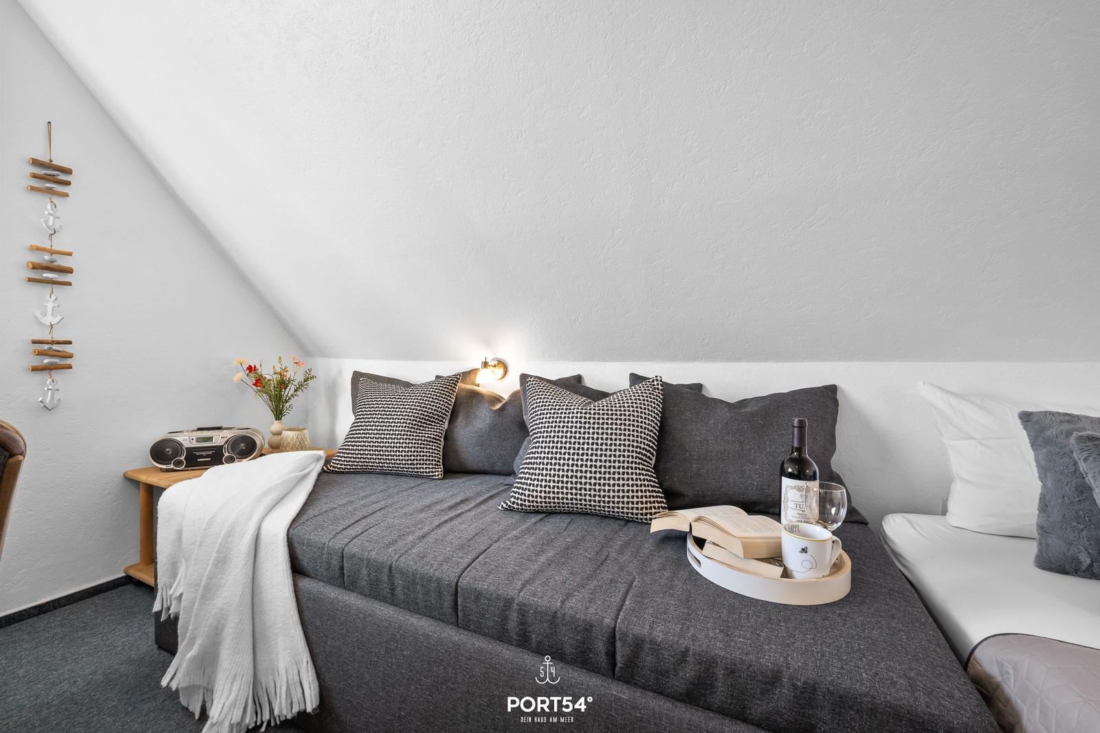 Doppelbett mit Kissen und Getränken unter schräger Decke