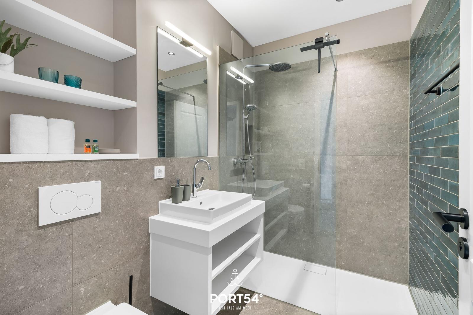 Moderne Dusche mit Glaswand, Waschbecken und Regal. Wandfliesen in Grau und Türkis.