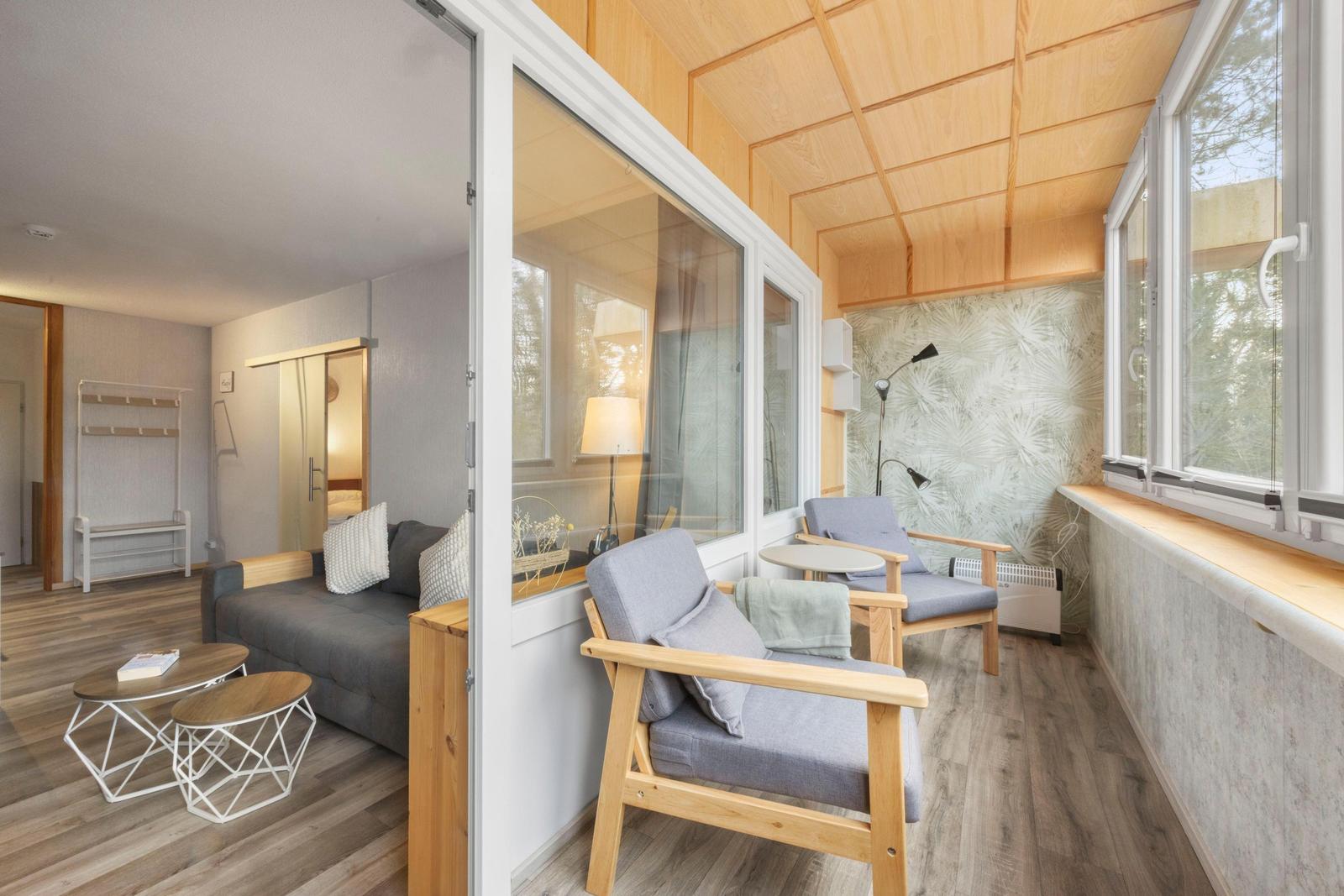 Wohnbereich mit Schlafsofa und Sitzbereich mit Fenstern und Holzdecke.