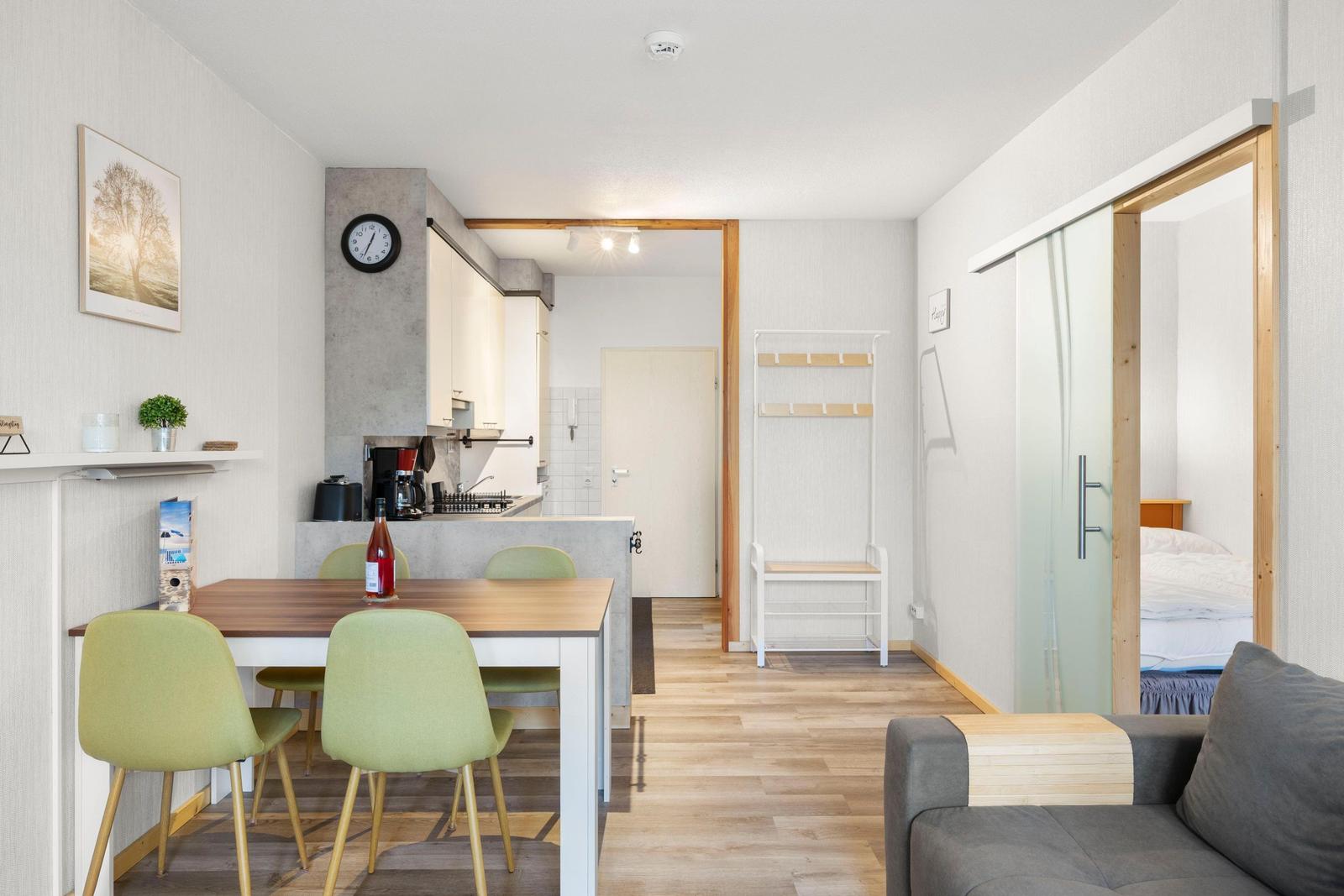 Wohnung mit Essbereich, Küche und Schlafzimmer. Holzfußboden und moderne Einrichtung.