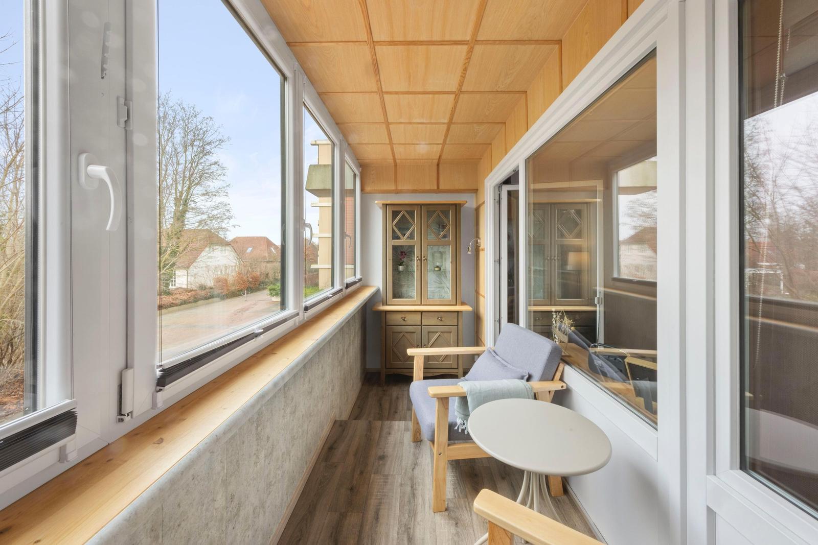 Terrasse mit Sitzgelegenheit und Blick auf Garten und Straße.