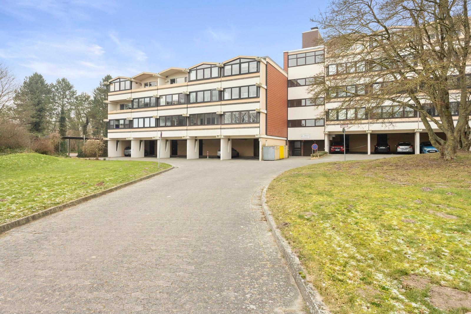 Modernes Mehrfamilienhaus mit Garagen und Grünanlagen.