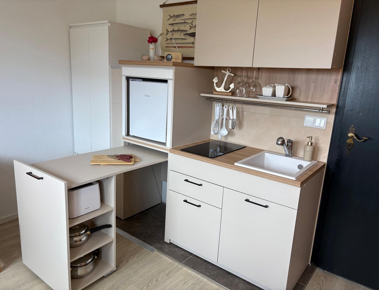 Küche mit Spüle, Herd, Kühlschrank und Arbeitsfläche