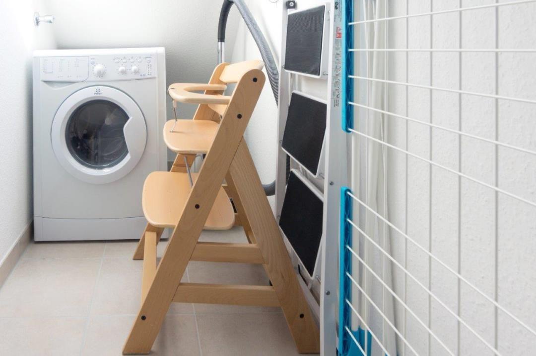 Wäschetrockner, Waschmaschine und hölzerner Kinderstuhl im Raum.