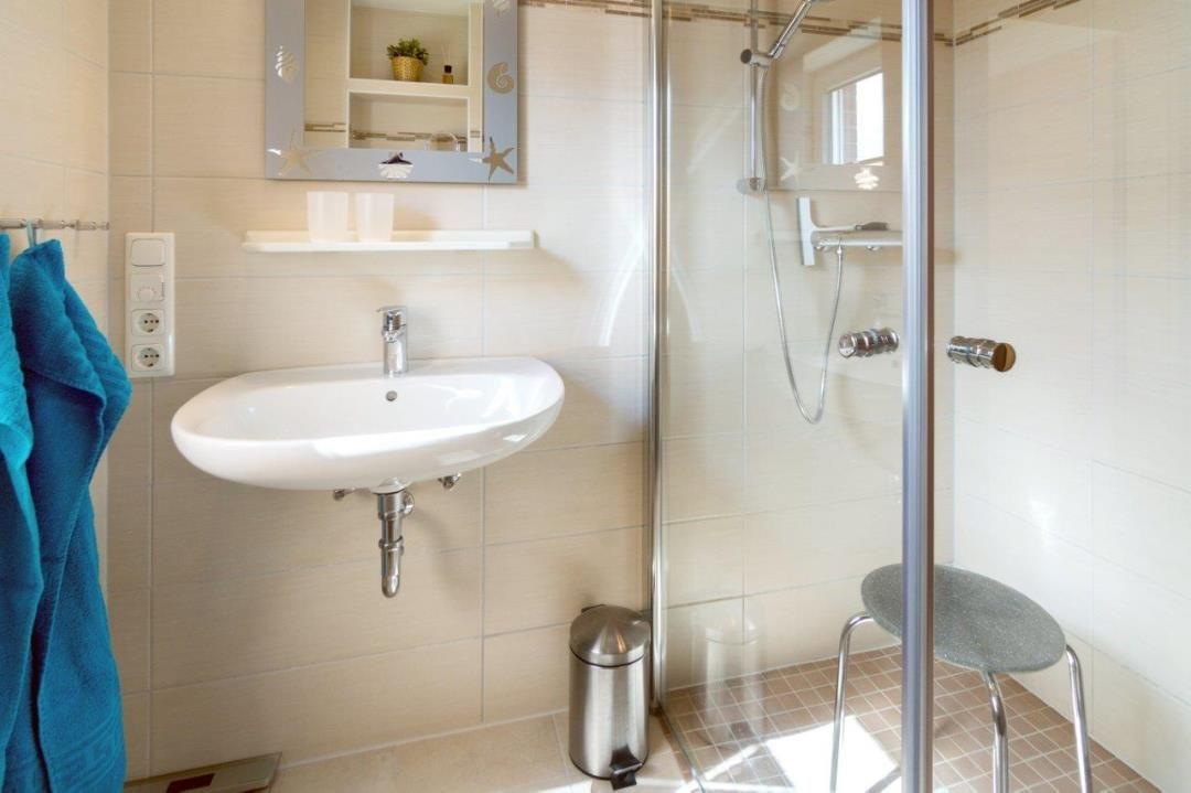 Badezimmer mit Dusche, Waschbecken und Spiegel