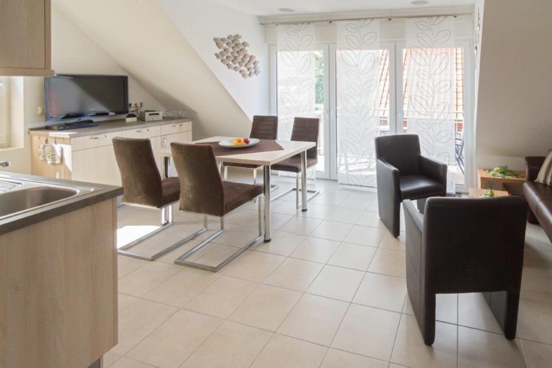 Küche, Essbereich und Wohnzimmer mit Tisch, Stühlen und TV.