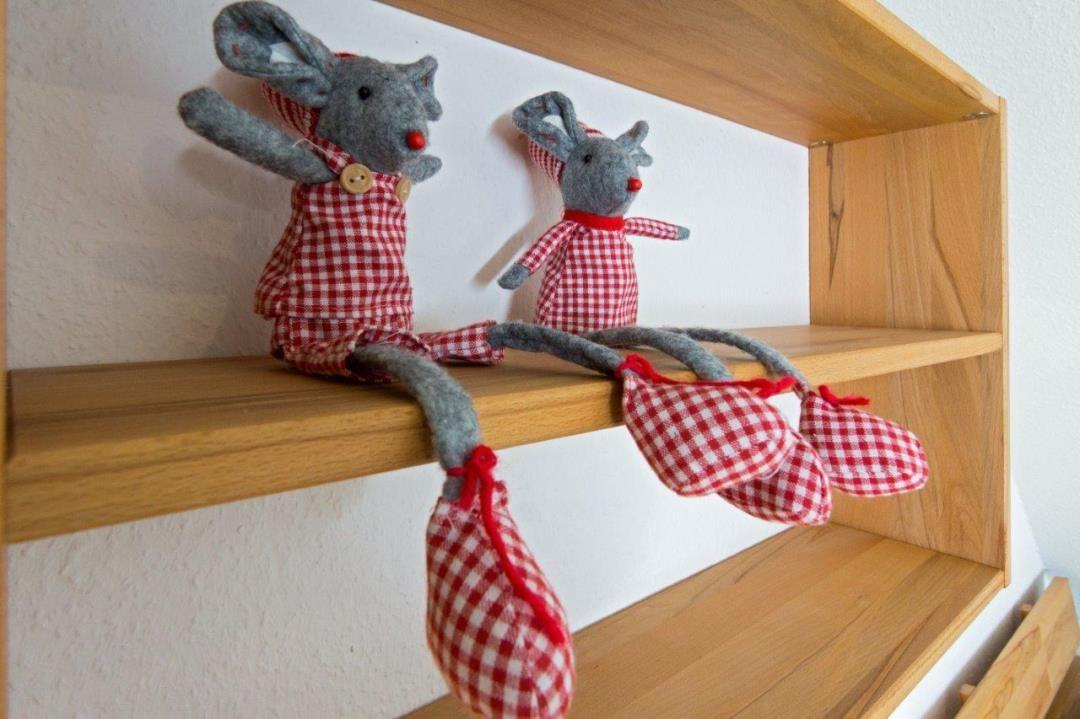 Zwei Stoffmäuse in karierten Kleidern sitzen auf einem Holzregal.