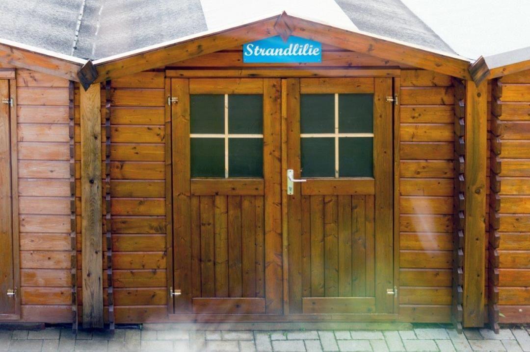 Holzschuppen mit Doppeltür und Schild Strandlilie