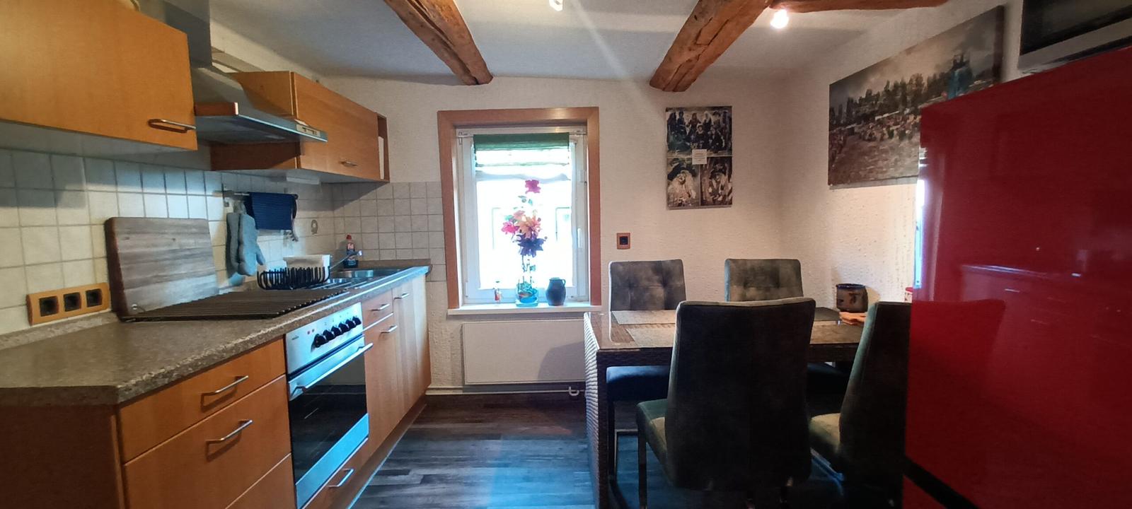 Küche mit Essbereich, Holzbalken und rotem Kühlschrank.