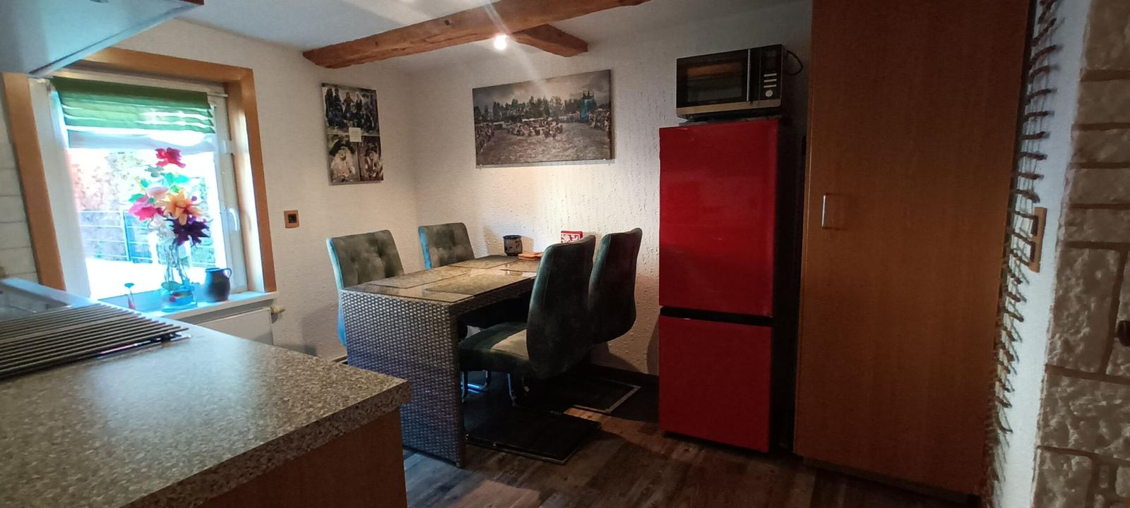 Esszimmer mit Tisch, Stühlen, rotem Kühlschrank und Fenster.