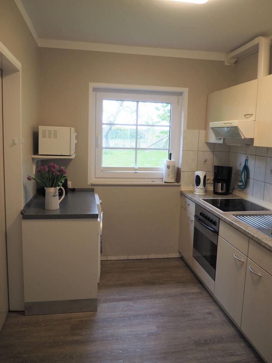 Küche mit Fenster, Spüle, Herd und Mikrowelle.