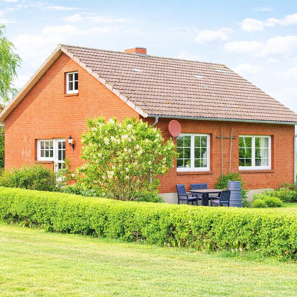 Rotes Backsteingebäude mit Garten, Terrasse und Sitzgelegenheit.