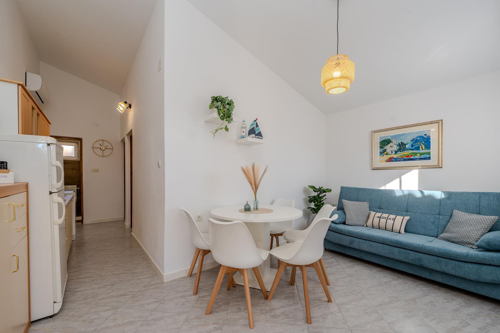 Dining area with table and chairs next to blue sofa and kitchen area.