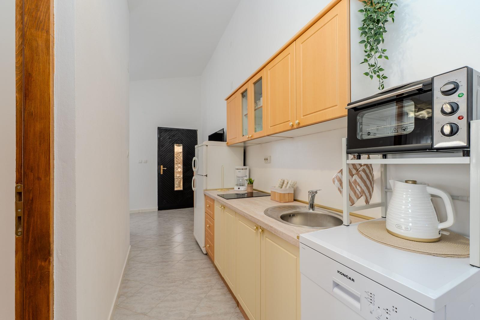 Kitchen with wooden cabinets, sink, refrigerator, and toaster oven.
