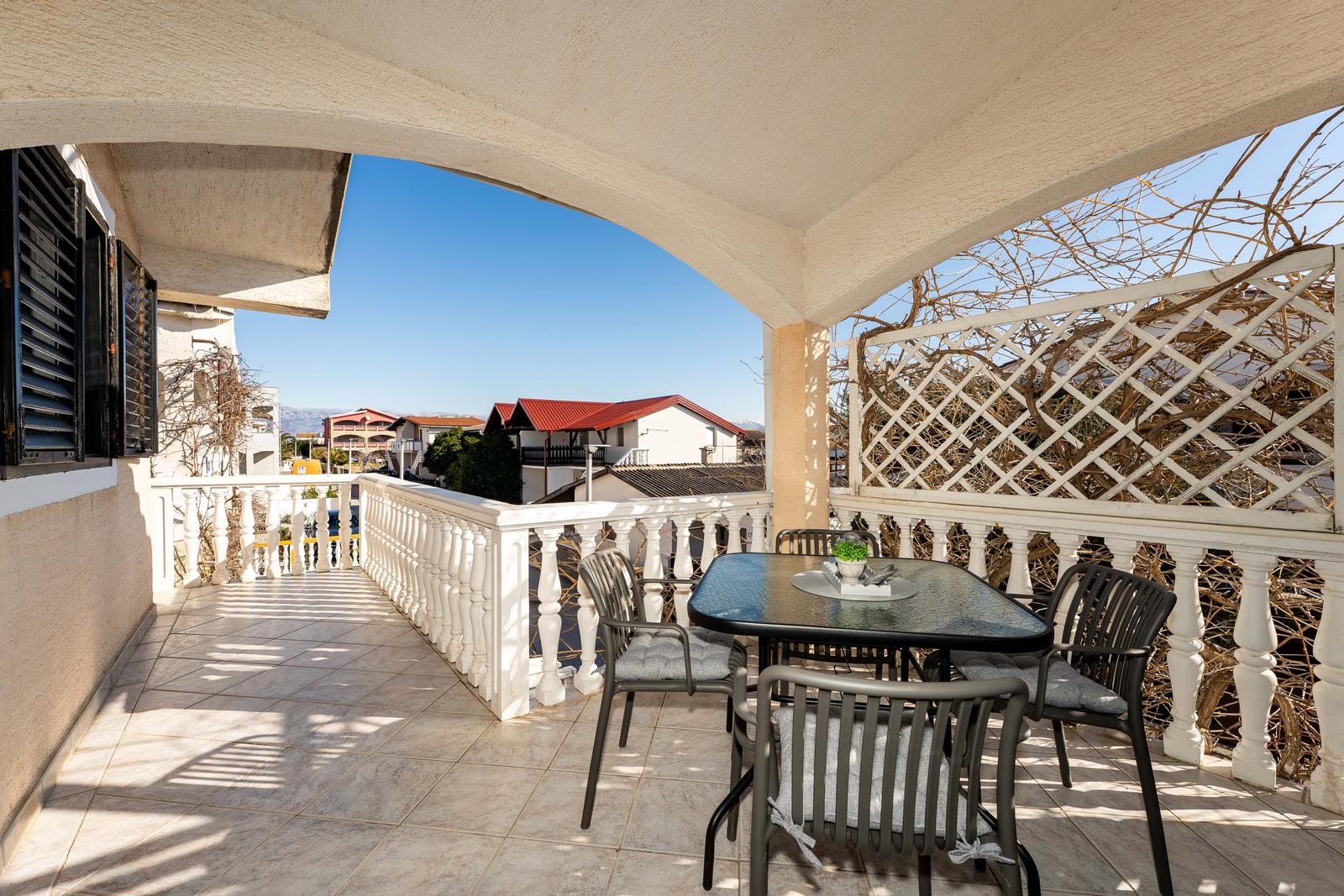 Terrace with table and chairs, view of buildings and sky.