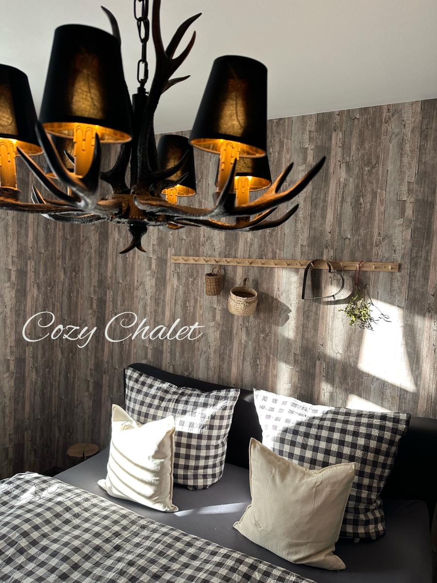 Schlafzimmer mit Hirschgeweih-Lampe und Holzwand