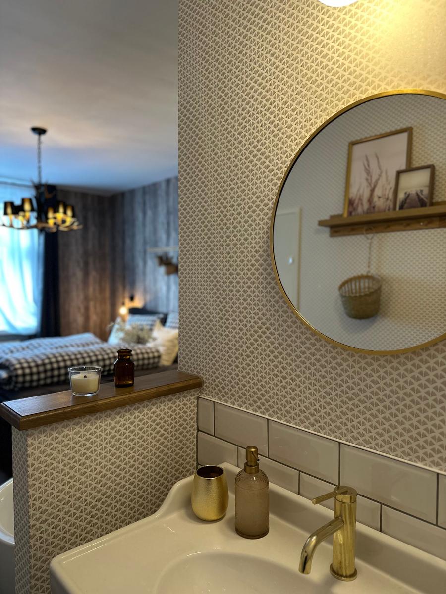 Waschbecken mit goldenem Wasserhahn und Spiegel an der Wand.