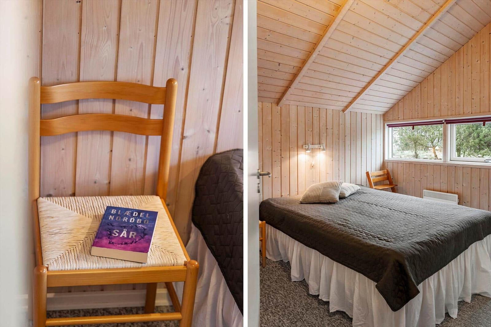 Schlafzimmer mit Holzwänden, Bett und Stuhl. Auf dem Stuhl liegt ein Buch.