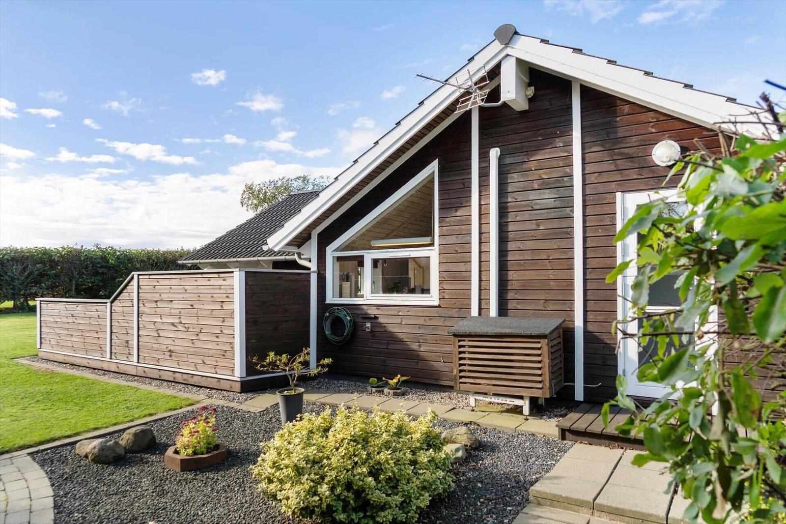 Holzhaus mit weißem Rahmen, Garten und Pflanzen.