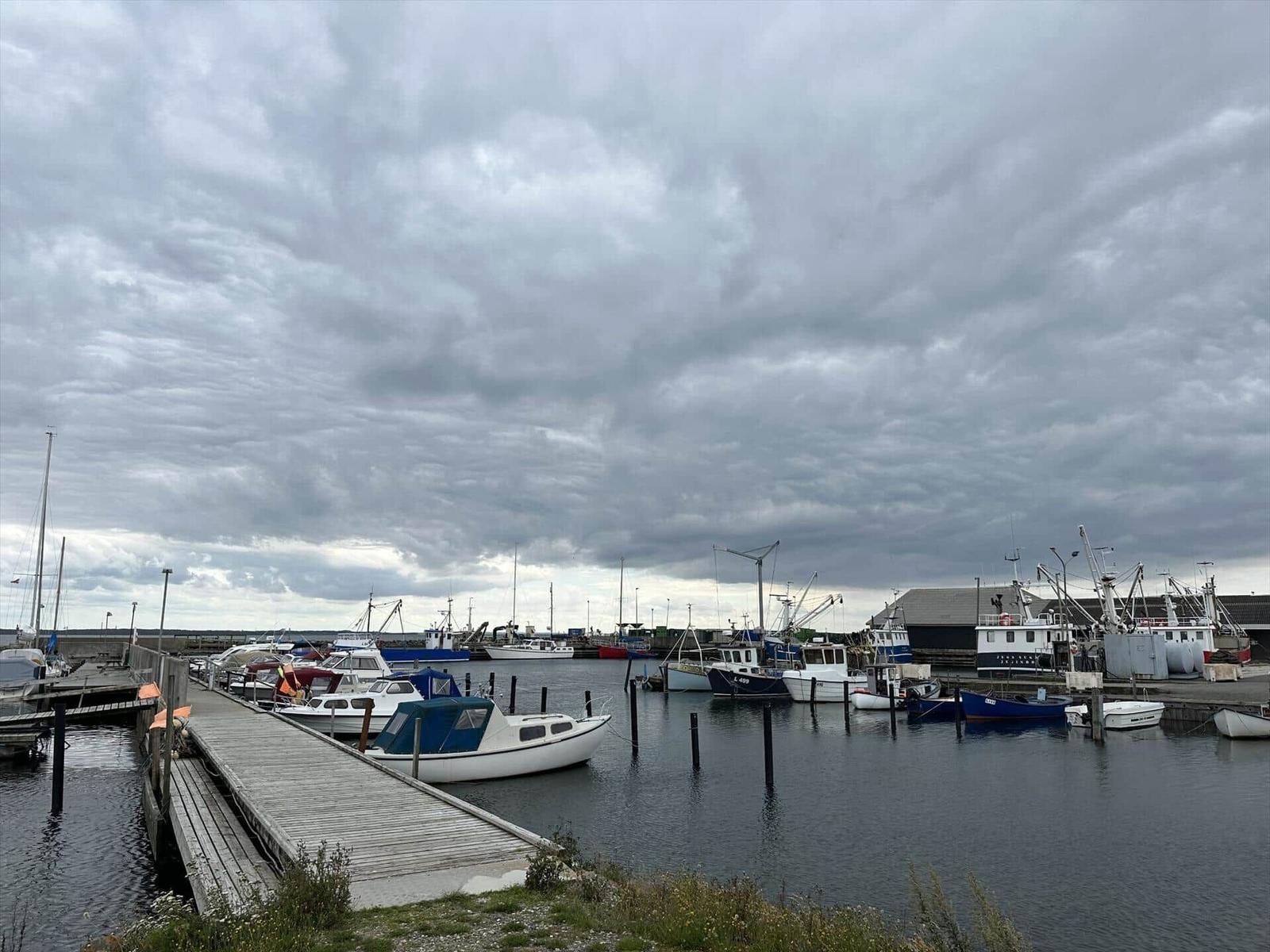 Hafen mit Booten und Steg unter bewölktem Himmel