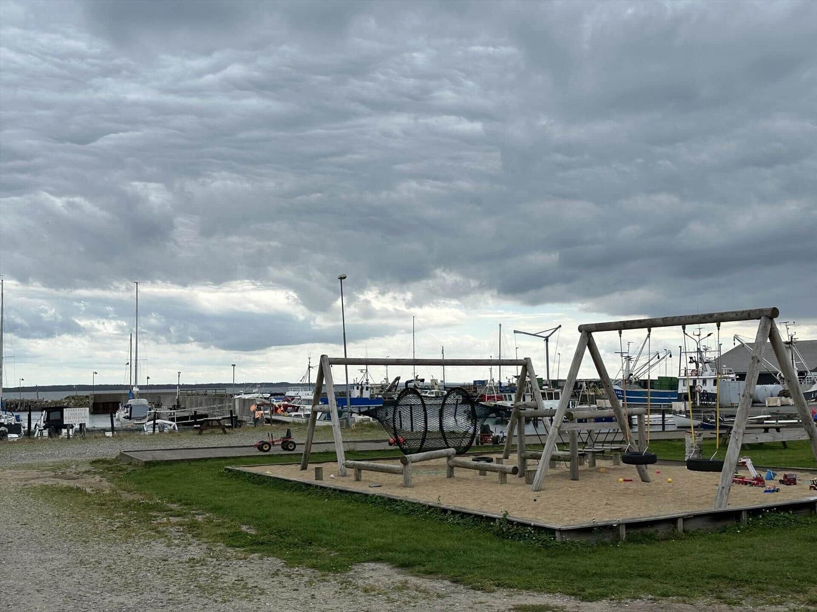 Kinderspielplatz mit Sandkasten und Schaukel am Hafen.