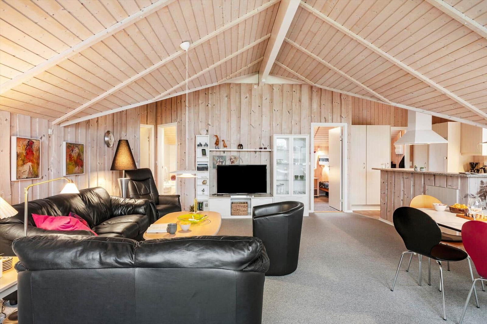 Wohn- und Essbereich mit Holzwand, Sofa und TV.